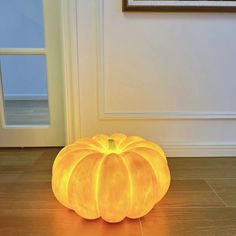 a glowing pumpkin sitting on the floor in front of a door