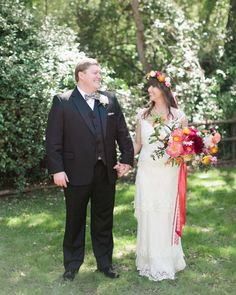 a bride and groom holding hands in the grass