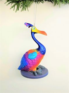 a colorful bird ornament hanging from a christmas tree