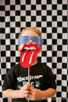 a young boy wearing sunglasses and holding a lollipop with the rolling stones on it