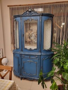 a blue china cabinet sitting next to a potted plant