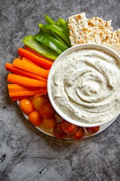 a plate with carrots, celery, crackers and dip