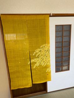 an open door with yellow curtains and a tree painted on it