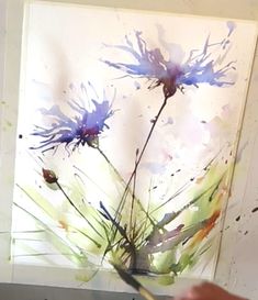 a person is painting flowers with watercolors