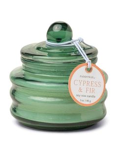 a green glass jar with a tag on the top and bottom that says cypress & fir