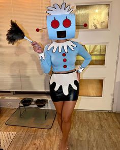 a woman in a costume holding a broom and posing for the camera while standing on a hard wood floor