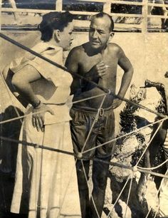 an old black and white photo of two men on a boat talking to each other