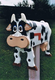 a cow mailbox sitting on top of a wooden post