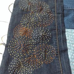 a pair of jeans with embroidered circles on them