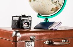 an old suitcase with a camera and a globe on top