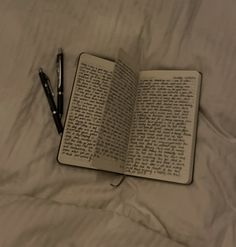 an open book with writing on it and a pen laying next to it in the bed