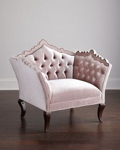 a pink chair sitting on top of a hard wood floor next to a white wall