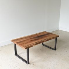 a wooden table sitting on top of a white floor next to a black metal frame