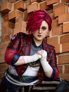 a woman with red hair sitting in front of a brick wall and holding her hands together