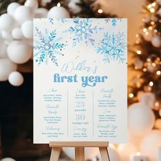 a first year sign sitting on top of a wooden easel in front of a christmas tree