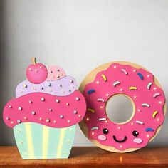 a pink doughnut with sprinkles and an apple on top is next to a cardboard cutout of a donut