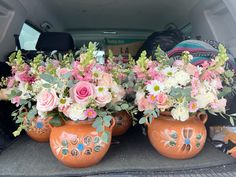 three vases filled with flowers sitting in the back of a car