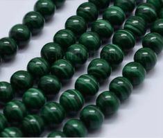 green glass beads are lined up on a white surface