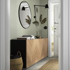 an entryway with a mirror, plant and books on the shelf next to it