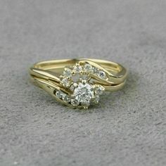 two gold wedding rings with diamonds on the top and bottom, sitting on a gray surface