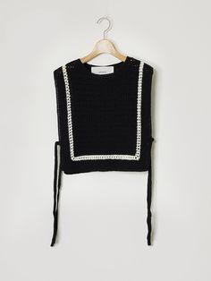 a black sweater with white trims and a tie around the neck is hanging on a hanger