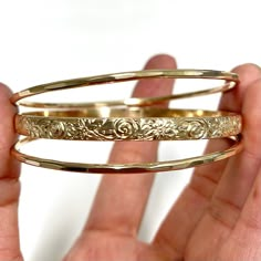 This listing is for a set of 1 heirloom and 2 hammered bangles. Hawaiian heirloom bangle is make with decorative floral pattern wire. Bangle is hand- formed, hammered and polished for a stunning texture and shine. It looks great worn alone or paired with other shell and charm bangles to create a chic, fun beachy look. Heirloom bangle is about 5mm wide 1.5mm thick. Each bangle is custom made to order so can not be return or exchange for that reason. PLEASE NOTE THERE IS A SLIGHTLY VISIBLE SOLDER Elegant Stackable Brass Bangle, Elegant Hammered Brass Bangle, Bangle Aesthetic, Damascene Jewelry, Hammered Bangles, Charm Bangles, Bangles Set, Mixed Metal Jewelry, Jewelry Accessories Ideas