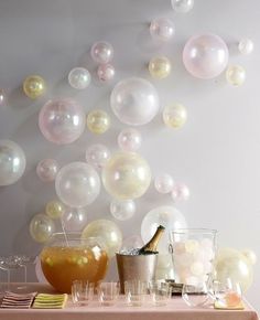 a table topped with glasses and bottles filled with liquid next to balloons that say congrats grads