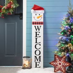 a snowman welcome sign next to a christmas tree