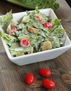 lettuce and tomato salad with croutons in a white bowl on a wooden table