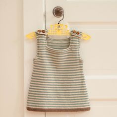 a knitted dress hanging on a door hanger in front of a white door