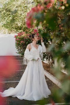 a woman in a white wedding dress is standing on the street and talking on her cell phone