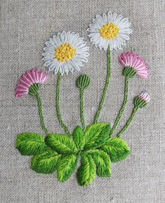 three daisies with green leaves and pink flowers on a beige background, embroidered onto fabric