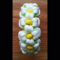 three white and green flowers are on a wooden table, one is made out of plastic beads