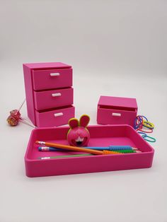 a pink plastic drawer with toothbrushes, pencils and other items in it