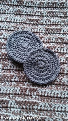 two crocheted coasters sitting on top of a brown and white blanket next to each other