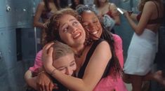 two women hugging each other in front of lockers with girls standing around behind them