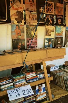 a wooden table topped with lots of records next to a wall covered in pictures and posters