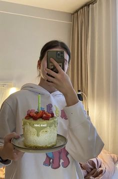 a woman taking a selfie while holding a cake