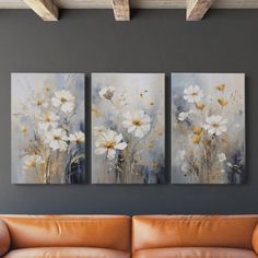 three paintings are hanging on the wall above a couch in front of a brown leather sofa