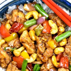 chicken and vegetable stir fry with chopsticks in a blue bowl on top of rice