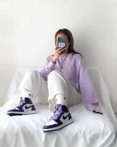 a woman sitting on top of a bed taking a selfie with her cell phone