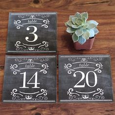 chalkboard table numbers are displayed next to a potted plant on a wooden table