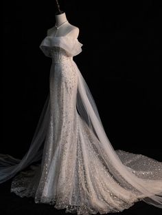 a white wedding dress on display in front of a black background with the veil pulled back