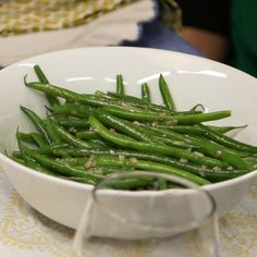 a white bowl filled with green beans on top of a table