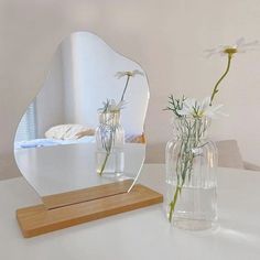 two vases with flowers in them sitting on a table next to a mirror that says rolling snow