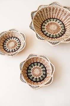 three bowls with designs on them sitting on a table