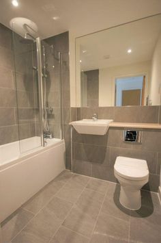 a bathroom with a toilet, sink and bathtub next to a mirror on the wall