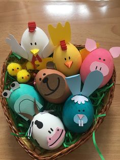 an easter basket filled with painted eggs and small toy animals on top of green grass