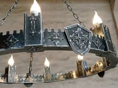 a metal chandelier with candles lit in the shape of shieldes and crosses