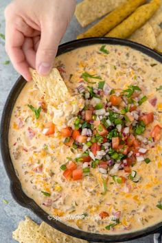 a hand dipping tortilla chips into a bowl of quesadilla dip